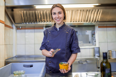 Smiling young cooker in the kitchen looking busyの写真素材