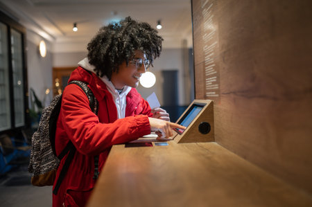 Curly-haired guy in eyeglasses buying tickets online and looking involved