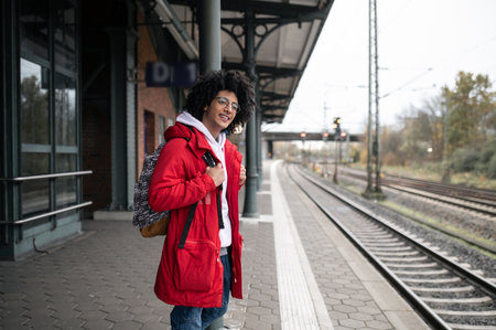 Guy in red jacket and with backpack waiting for the train at the platform