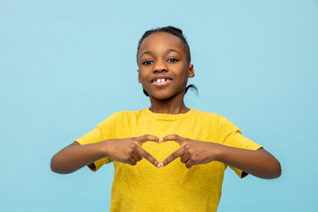 Smiling African American little boy making heart shape gestureの写真素材