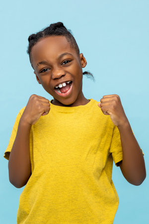Extremely happy African American little boy rejoicing with clenched fists