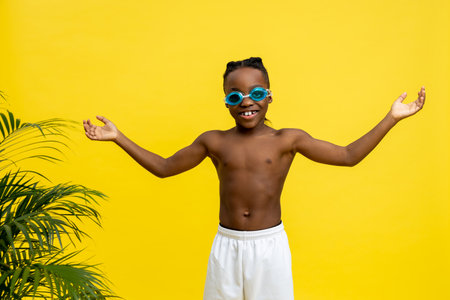Dark-skinned boy on yellow background looking excited and contentedの写真素材