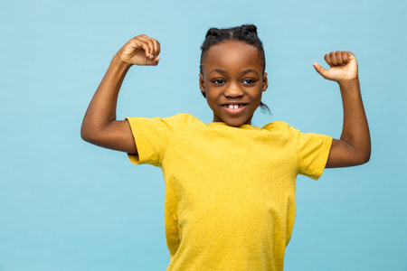 Dark-skinned boy in yellow tshirt with his hands up