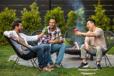 Satisfied men friends toasting beer during summer picnic
