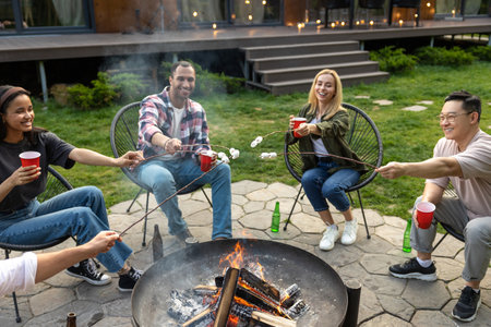 Young happy friends having picnic having fun and celebrating while grilling at barbecue party