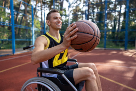 Young guy athlete having disability in wheelchair having basketball trainingの写真素材