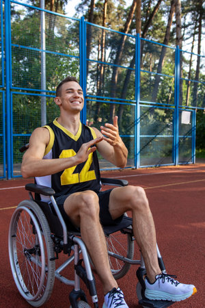 Sporty guy with disability maneuvering wheelchair engaging in basketballの写真素材
