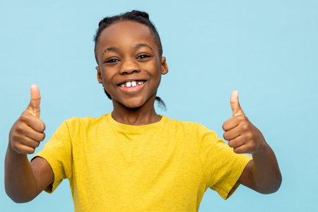 Cute dark-skinned boy looking excited and smiling nicelyの写真素材