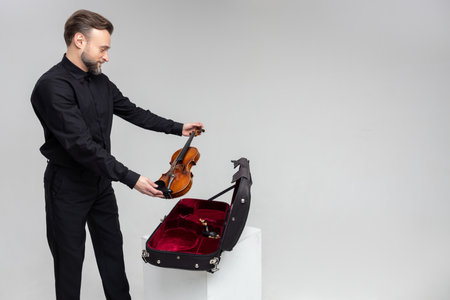 Bearded man artist packing musical instrument in violin case