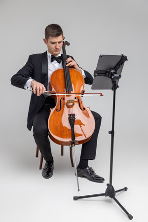 Man artist wearing tuxedo playing cello with music note