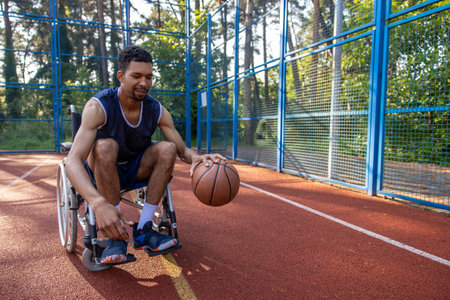 Man basketball player in wheelchair playing basketball alone on courtの写真素材
