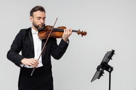 Violinist virtuoso in tuxedo performs melody on classical violin