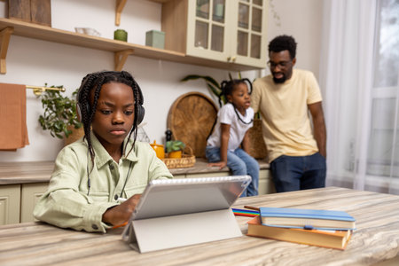 Black little girl taking class online using digital tablet