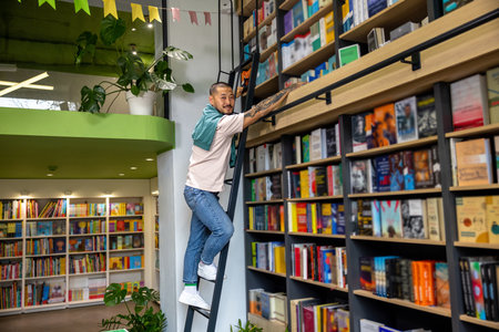 Bald asian young man searching for a needed book at the bookshelvesの写真素材