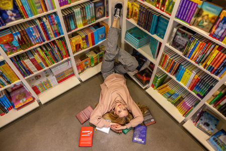 Top view of a blonde woman lying on the floor at the libraryの写真素材