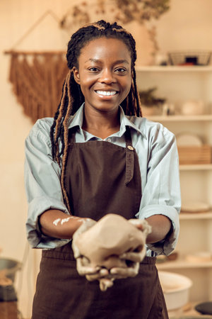 Young female sculptor with a piece of wet clay in hands