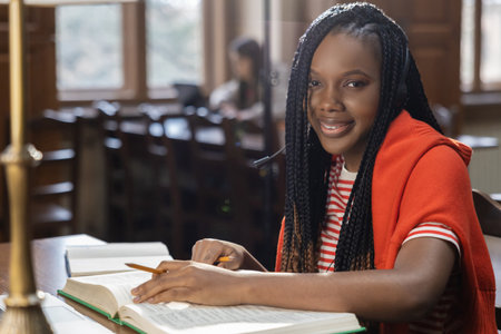 Cute african american young woman sitting at the table in the library
