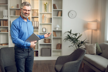 Man psychologist wearing blue shirt holding clipboard standing in his officeの写真素材