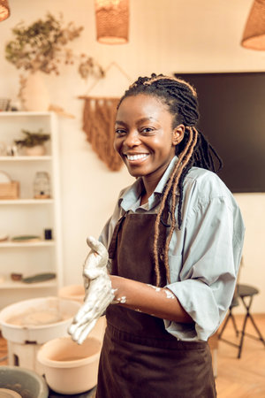 Smiling young woman with a new clay mug in hands