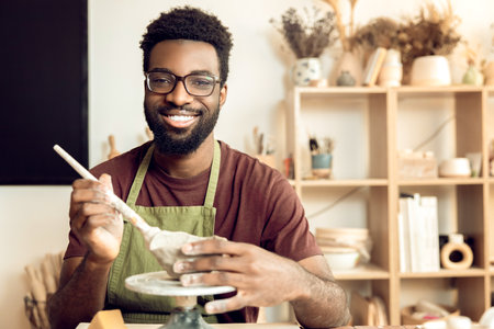 Smiling man painting pottery and looking enjoyed