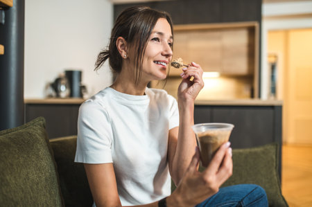 Cute young woman eating dessert from the glass and looking enjoyedの写真素材