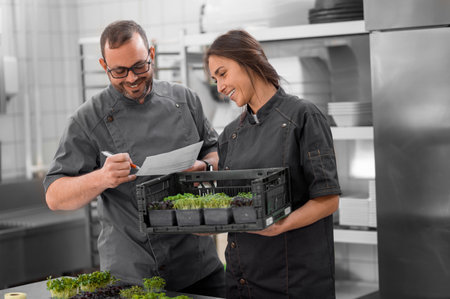Professional cooks holding microgreen in small boxes in restaurant kitchen