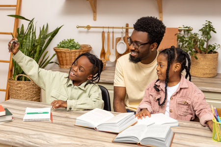 Handsome father and his cute little daughters making selfie using phone while doing homeworkの写真素材