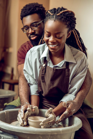 Happy couple smiling and looking inspired working on a pottery wheelの写真素材