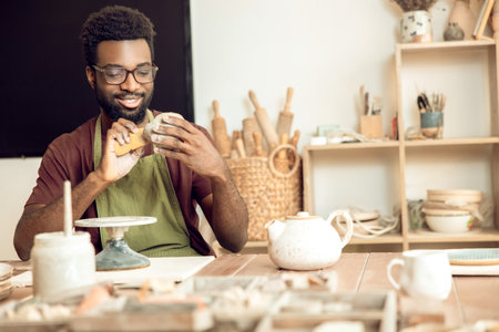Man in apron working in the pottery studio and looking involved