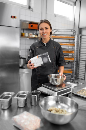 Experienced chef in professional kitchen preparing dough with flour to make breadの写真素材