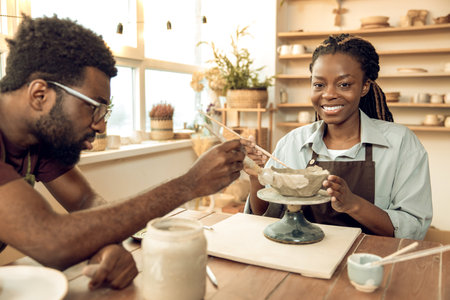 Man and woman looking focused while working with potteryの写真素材