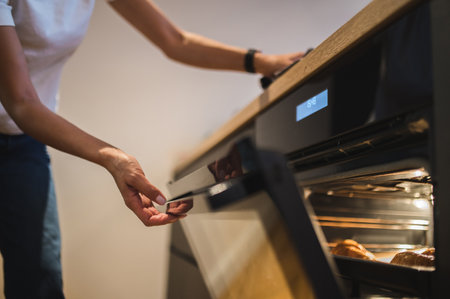 Woman baking croissants in the oven at home