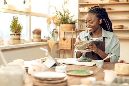 Dark-skinned beautiful sculptor conducting online class on ceramics
