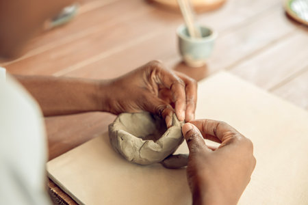 Close up picture of hands molding a shape of a clay