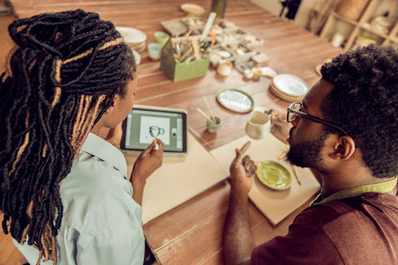Two people sitting at the table and working with pottery