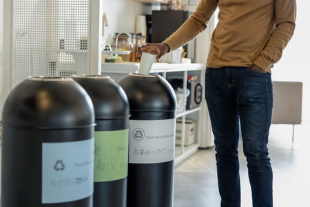 Waste separation and recycling, man throwing out paper cup into binの写真素材