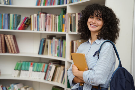 Smiling pretty woman in the library near the book shelve