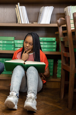 Long-haired african american woman reading a book and looking involved