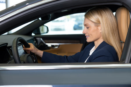 Long-haired blonde business woman at the steering wheel in a car