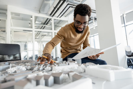 Dark-skinned young architect working in the office and looking tired