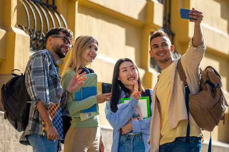 Cheerful students making group selfie in university campus after classes