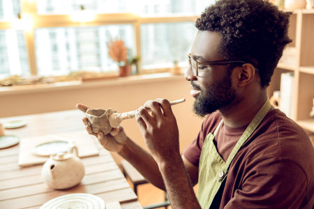 Male sculptor working on a new clay mug in his office