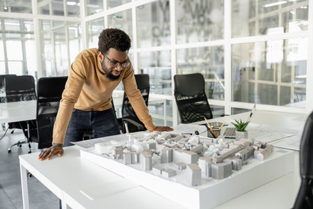 Dark-skinned curly-haired architect working on the mockup and looking focused