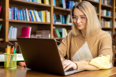Young blonde woman working on a laptop in the library