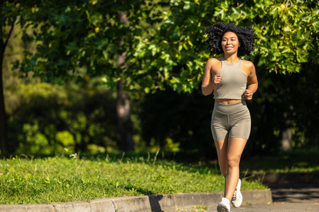 Woman in summer sportswear running in a sunny par and looking focusedの写真素材