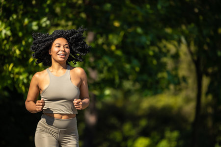 Woman in summer sportswear running in a sunny par and looking focusedの写真素材
