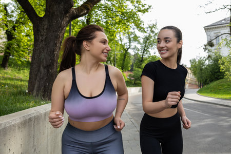 Plus-size woman losing weight while running with her trainer in stadium outdoorsの写真素材