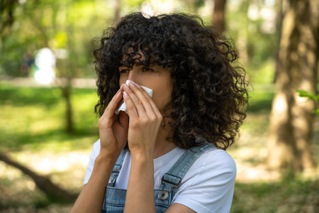 Curly-haired young woman suffering from seasonal allergy