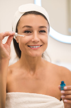 Woman applying anti-age serum on her skinの写真素材