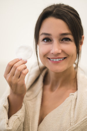 Pretty caucasian young woman cleaning her face with a spongeの写真素材